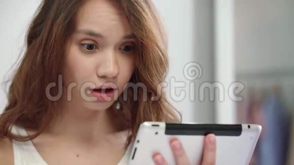 惊讶的女人脸看着平板电脑令人震惊的女人情绪视频的预览图