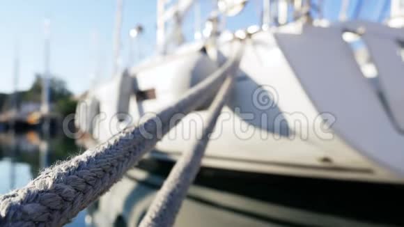 白色游艇停泊在海湾绳子在框架中摆动靠近视频的预览图