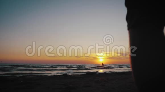 父亲和他的小女儿的剪影在日落时快乐地跑进大海有孩子的幸福家庭视频的预览图