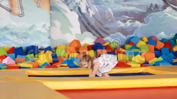 快乐的女孩在孩子们的操场上蹦床上跳视频的预览图