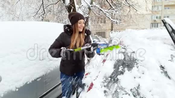 4k镜头微笑的年轻女子骑车上班前在雪地上擦车视频的预览图