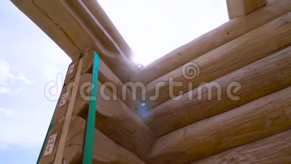 阳光天空背景下的新家园建设框架剪辑新原木和未完工木屋的底部景观视频的预览图
