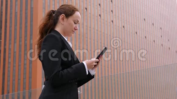 穿着西装的女人在市中心的智能手机里发短信视频的预览图