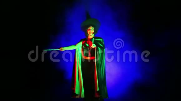 一个年轻的女人伪装成女巫在烟雾和探照灯的灯光下视频的预览图