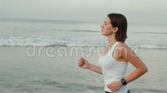 运动女跑步者穿着带表带的智能手表跑带空白黑色玻璃弯曲触摸屏的天然海洋海滩视频的预览图