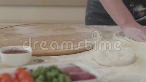 在厨房里把年轻的披萨制造商的双手合拢在厨房里形成一个比萨饼皮捏面团披萨视频的预览图