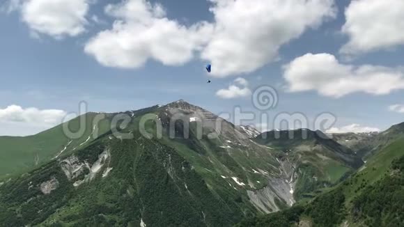 白种人绿山中的滑翔伞美景视频的预览图