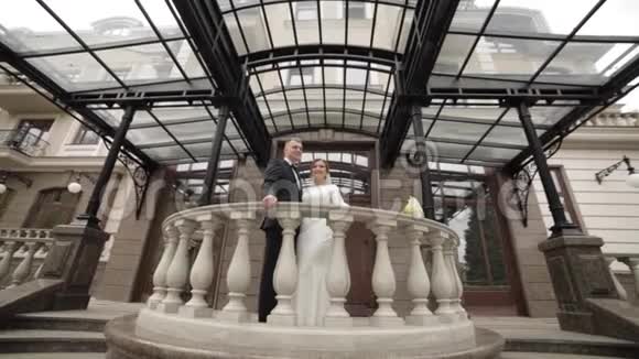 幸福的新婚夫妇站在宫殿旁美丽的阳台上视频的预览图