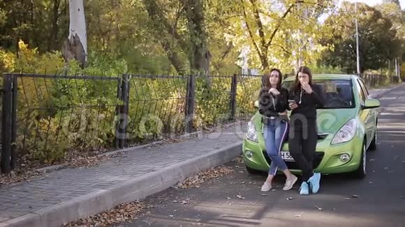 两个女人站在一辆停着的绿色汽车的引擎盖上说话视频的预览图