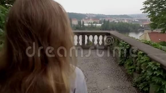 金发女郎走在露天露台上城市山坡上有石质阳台视频的预览图