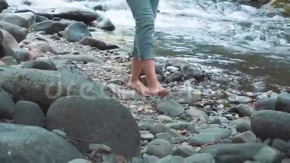 光着脚近距离射杀年轻的旅行者游客在Borjomi冰冷的河流上没有鞋子的石头行走视频的预览图