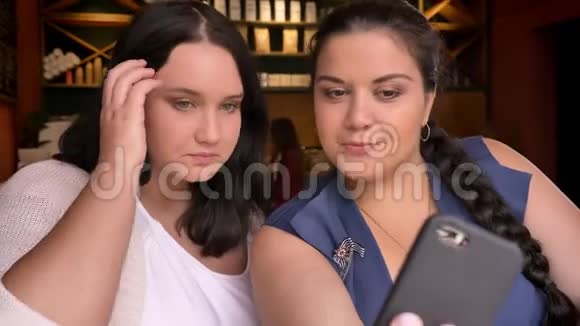 两个肥胖的白种人女朋友在咖啡馆里拍照片脸上带着微笑视频的预览图