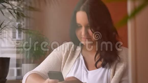一个大而集中的白种人女孩在咖啡馆里拿着画报和打字视频的预览图