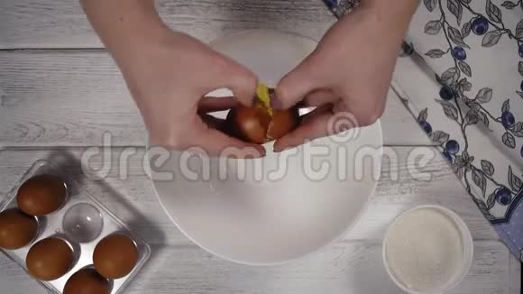 特写镜头女人双手把蛋黄从白壳里倒入白盘视频的预览图