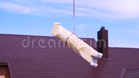 蓝色多云的天空背景上悬挂在一根建筑绳上的短原木剪辑木屋建筑材料视频的预览图