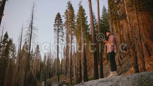 年轻的男摄影师在约塞米蒂山公园慢镜头拍摄美丽的森林日落视频的预览图