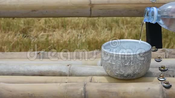 竹桌上装有冰块的不锈钢碗盛满了水背景大米的收获视频的预览图