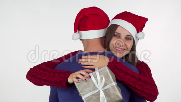戴着圣诞帽的迷人年轻女子抱着她的礼物视频的预览图