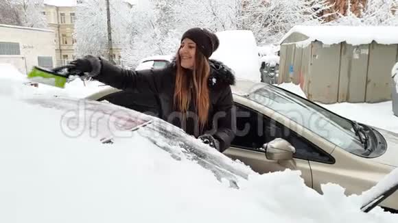 4k视频美丽的女司机早晨在暴风雪后清理汽车视频的预览图