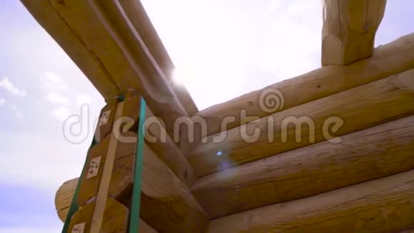 阳光天空背景下的新家园建设框架剪辑新原木和未完工木屋的底部景观视频的预览图