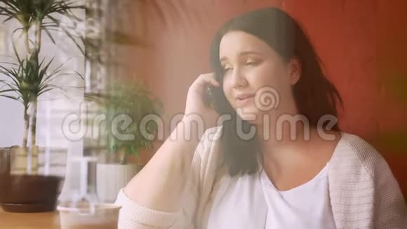 在靠近窗户的一杯咖啡的咖啡馆里一个浓白种人的模特通过电话交谈视频的预览图
