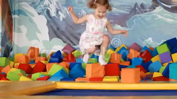 快乐的女孩在孩子们的操场上蹦床上跳视频的预览图