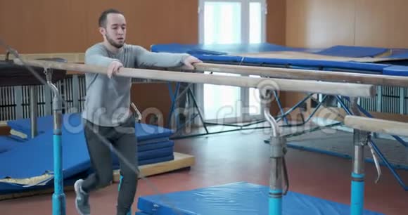 体操运动员在健身房的双杠上锻炼视频的预览图