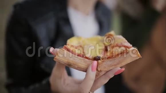 两个女人在城里的一个大盒子里吃披萨坐在长廊上的长凳上把一片比萨饼放进去视频的预览图