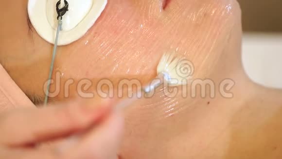 特写美容师在女孩的脸上涂了一种刷子保湿凝胶视频的预览图