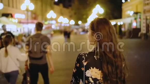 一个美丽的女孩走在夜城的街道上环顾四周视频的预览图
