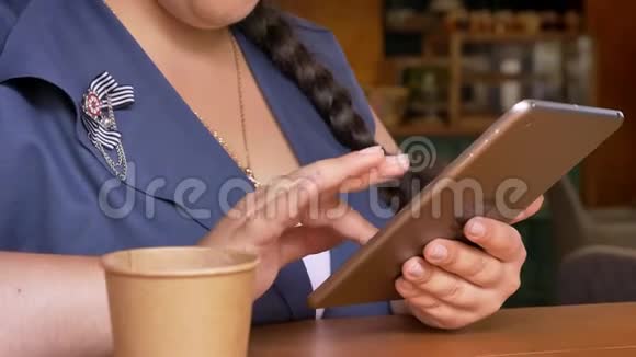 快乐的白种人女性在咖啡馆里滚动她的设备和喝酒视频的预览图