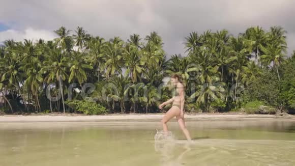 美丽的女人穿着比基尼在海边散步蚂蚁在炎热的日子掉进淡水里微笑的女人享受海水视频的预览图