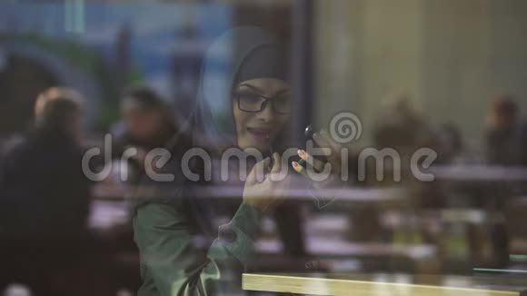 戴头巾的漂亮女士在咖啡馆涂口红对着镜子微笑卖弄风情视频的预览图