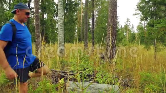 森林里的一位男性游客脱下背包坐在一棵倒下的树上视频的预览图