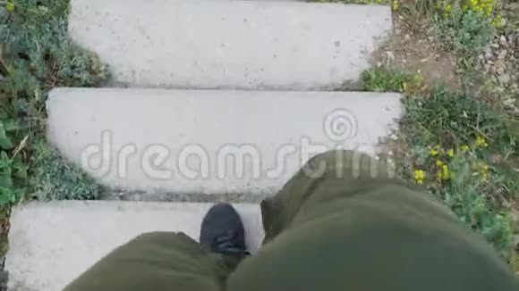 一个穿着绿色裤子和黑色靴子的年轻人慢慢地走下来然后沿着楼梯和混凝土台阶跑着视频的预览图