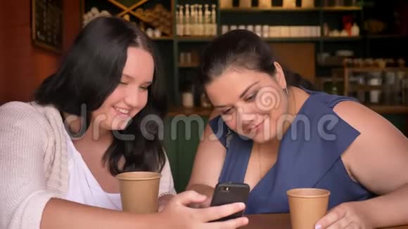 两个重白种人女人看着智能手机带着饮料的惊喜视频的预览图