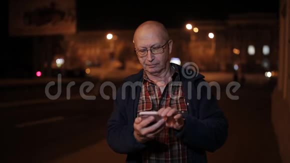 一个在路上过夜的老人使用智能手机视频的预览图