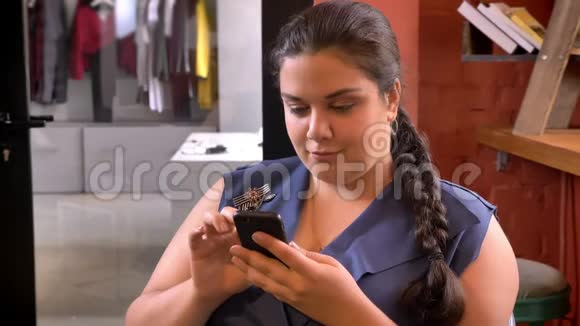 Ower加权白种人女性在她的手机和微笑室内打字视频的预览图