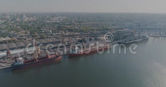 带着货船飞越港口通过港口起重机和大型货船飞行大型海港的总体计划视频的预览图