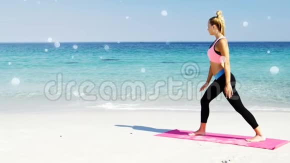 海滩上一位健身妇女在瑜伽垫上做运动的侧视图视频的预览图