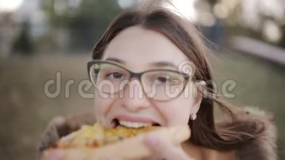 戴眼镜的女孩直接把一大片比萨饼咬进相机特写视频的预览图