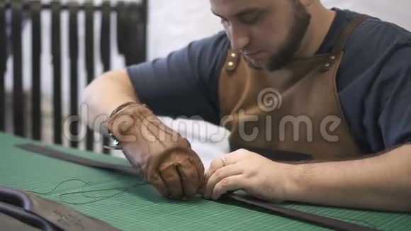工匠在车间用人造皮革制作的黑色袋子手柄上工作视频的预览图