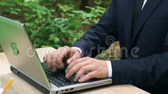穿着正式服装坐在森林里的笔记本电脑打字环保技术视频的预览图