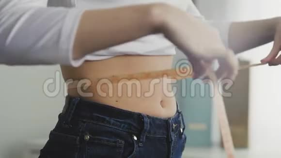 年轻女子用卷尺测量腰部的侧视视频的预览图