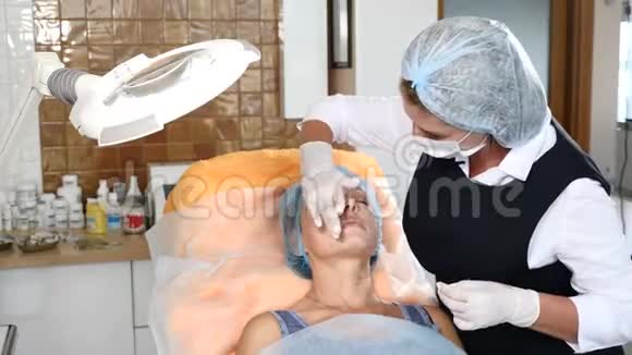 美容师将麻醉应用于一位资深女性客户女人准备接受美容治疗4k视频的预览图