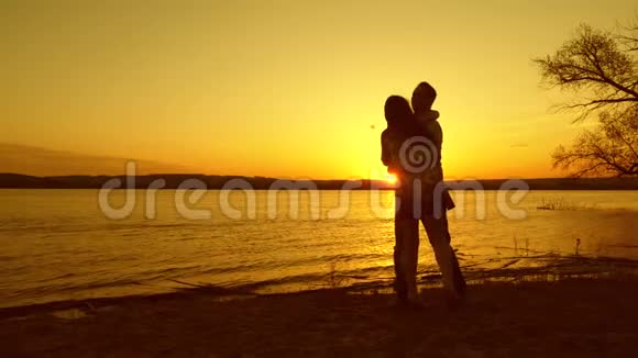 男人在快乐的女孩舞蹈中盘旋恋爱中的女孩和男人晚上在海滩上跳舞在黄色的夕阳下跳舞视频的预览图