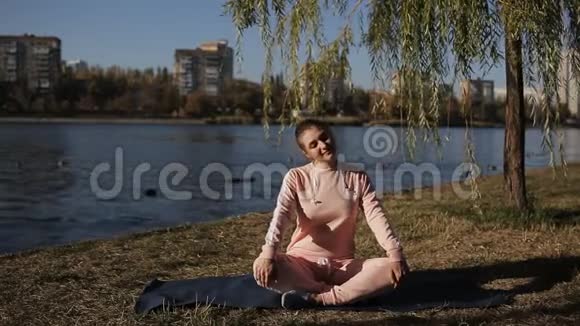 穿着运动服的女孩在河流瑜伽的背景下城市景观视频的预览图