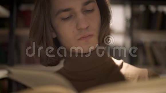 书橱之间翻书页的年轻人画像视频的预览图