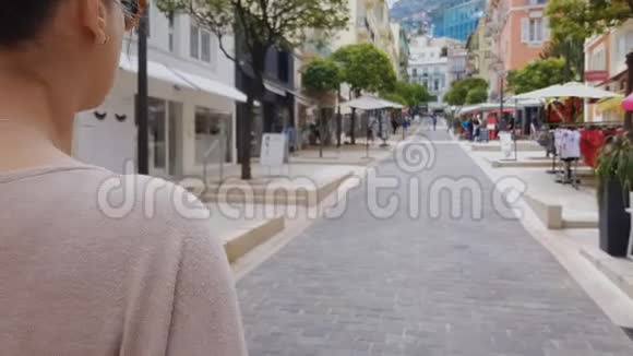 一位年轻的女士在街上和商店一起散步寻找销售欧洲城市视频的预览图