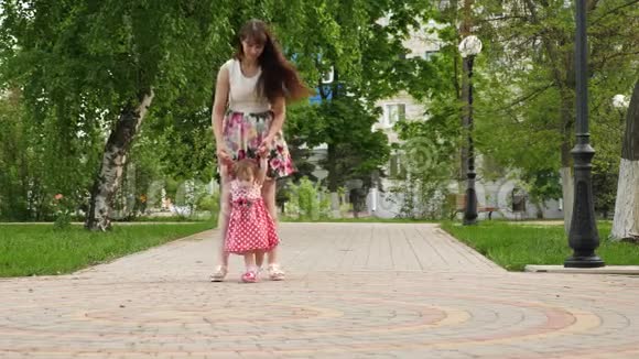 妈妈带着小宝贝去公园孩子学会走路带孩子的家长步行视频的预览图
